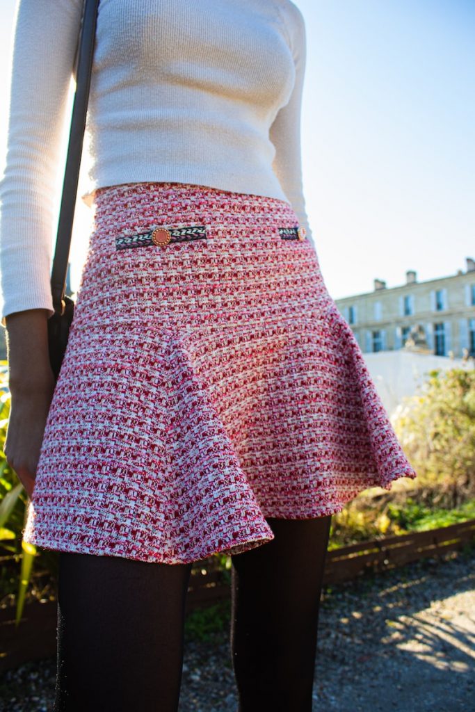 a woman wearing a patterned skirt and a white sweater showcasing a business professional outfit while Incorporating Patterns into Her Business Professional Wardrobe