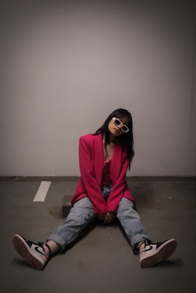 a woman sitting on the ground wearing sunglasses in a business casual outfit