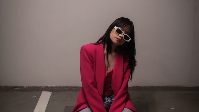 a woman sitting on the ground wearing sunglasses in a business casual outfit